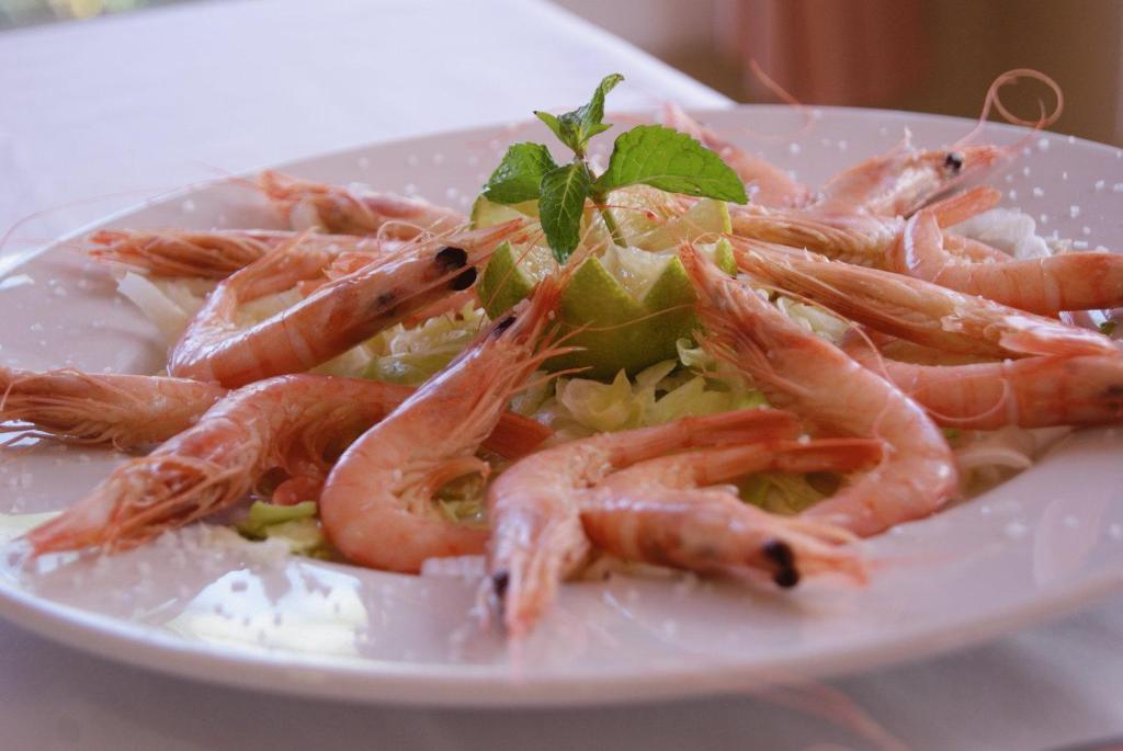a plate of shrimp and rice with a green garnishment at Hotel Ayamontino in Punta Umbría