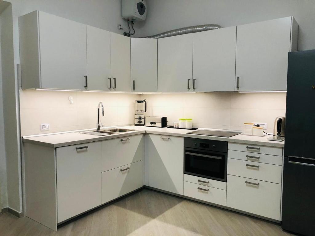 a kitchen with white cabinets and a black refrigerator at Casa Novesia in Carloforte