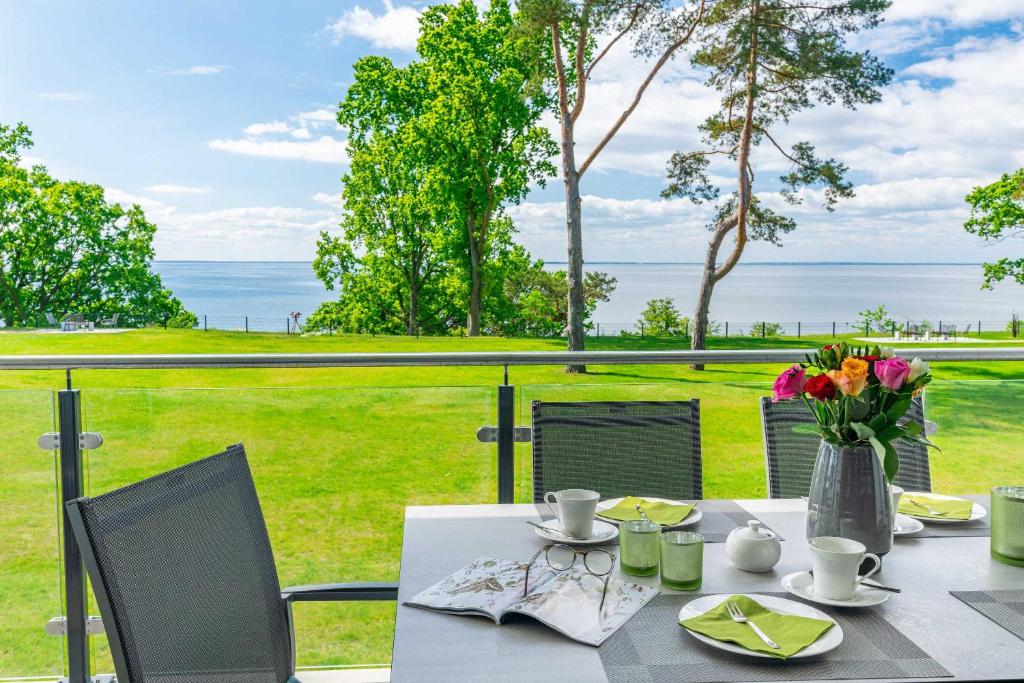 een tafel met een vaas met bloemen op een balkon bij Appartement "Wolkenschiff" - Oase am Haff in Garz