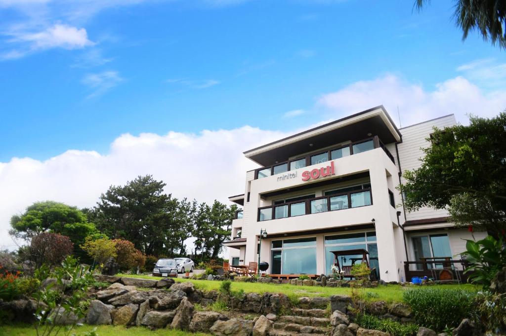 a white building with a garden in front of it at Minitel Soul in Seogwipo