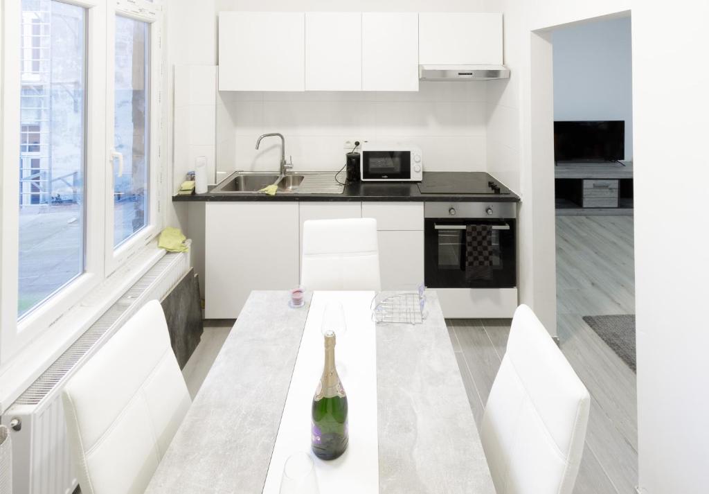 a white kitchen with a table with a bottle on it at GROGO DUPLEX APPARTMENT(CENTRE OF ANTWERP) in Antwerp