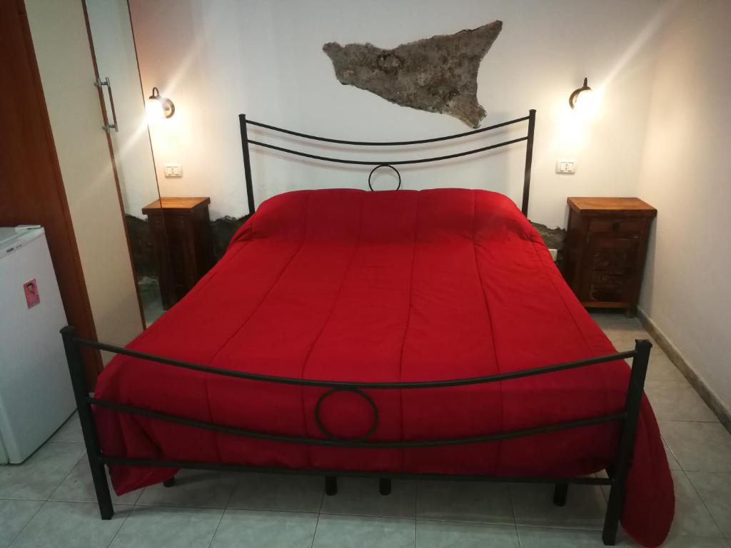 a red bed in a room with a red comforter at Casa del vico in Catania