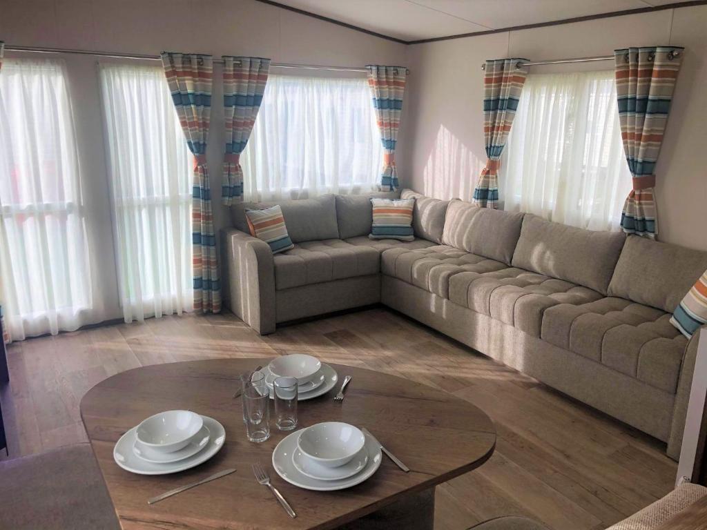 a living room with a couch and a table at Larch Superior Holiday Home in Chapel Saint Leonards