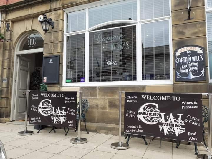 a store with signs in front of a building at Captain Wills Apartment in Filey