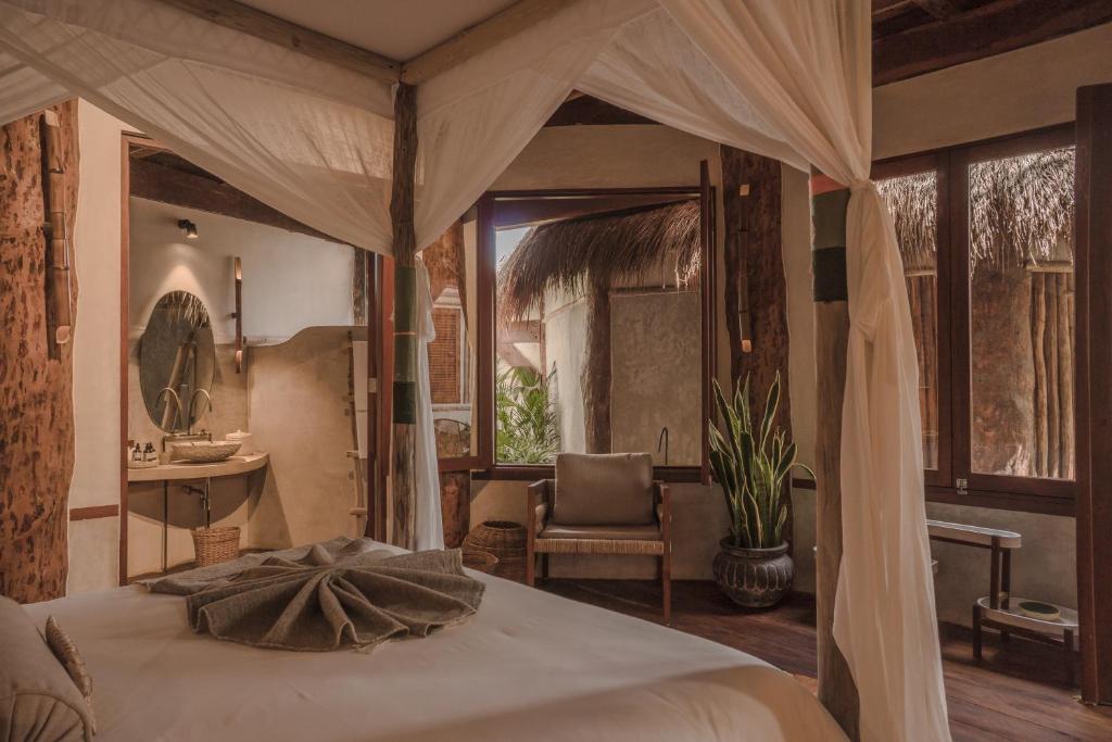 a bedroom with a canopy bed and a chair at Delek Tulum in Tulum