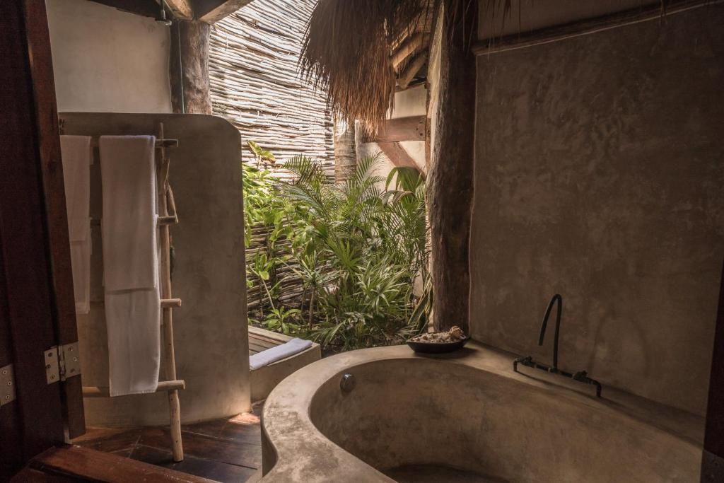 a bath tub in a bathroom with a window at Delek Tulum in Tulum