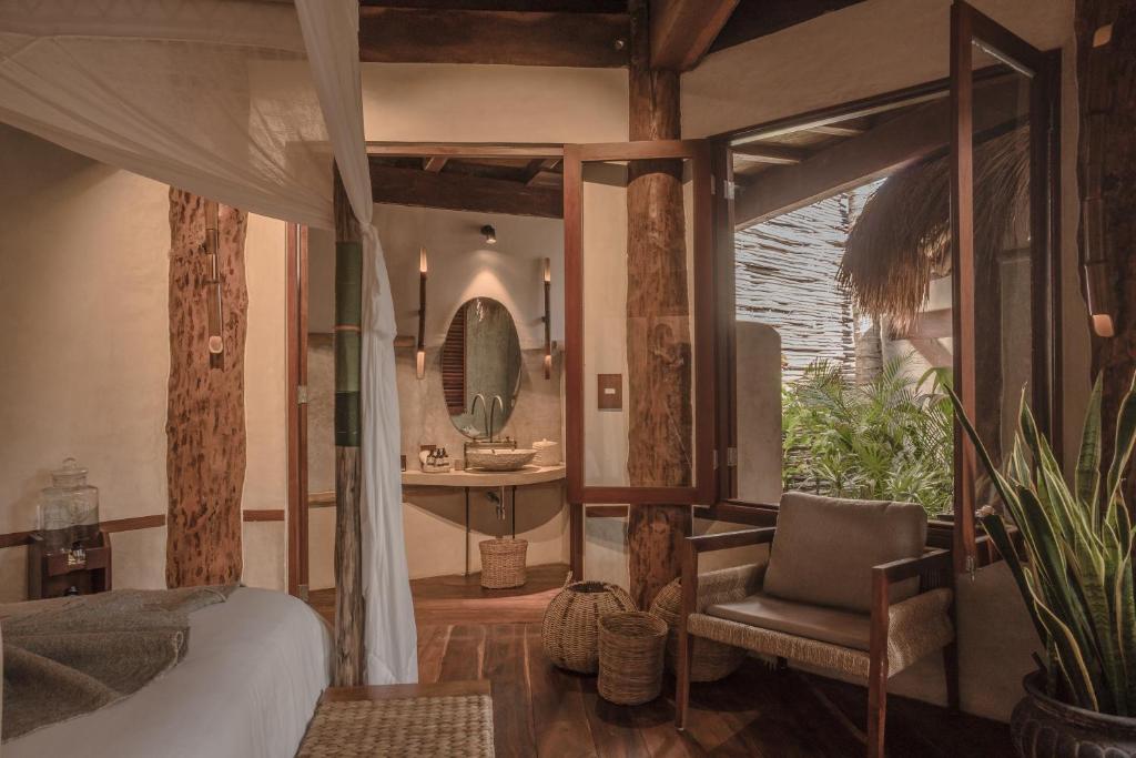 a bedroom with a bed and a chair and a mirror at Delek Tulum in Tulum