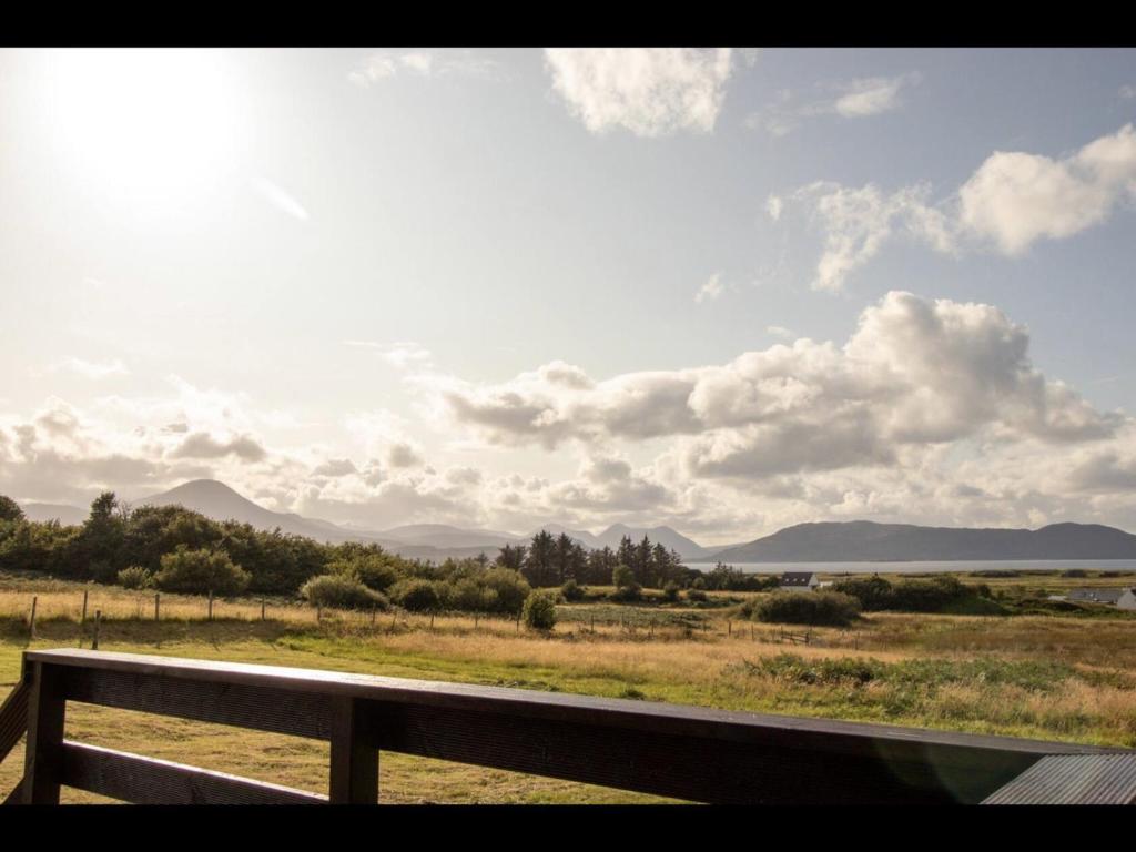 a bench in a field with a view of the mountains at Breakish Bay Pods (Pod 2) in Breakish