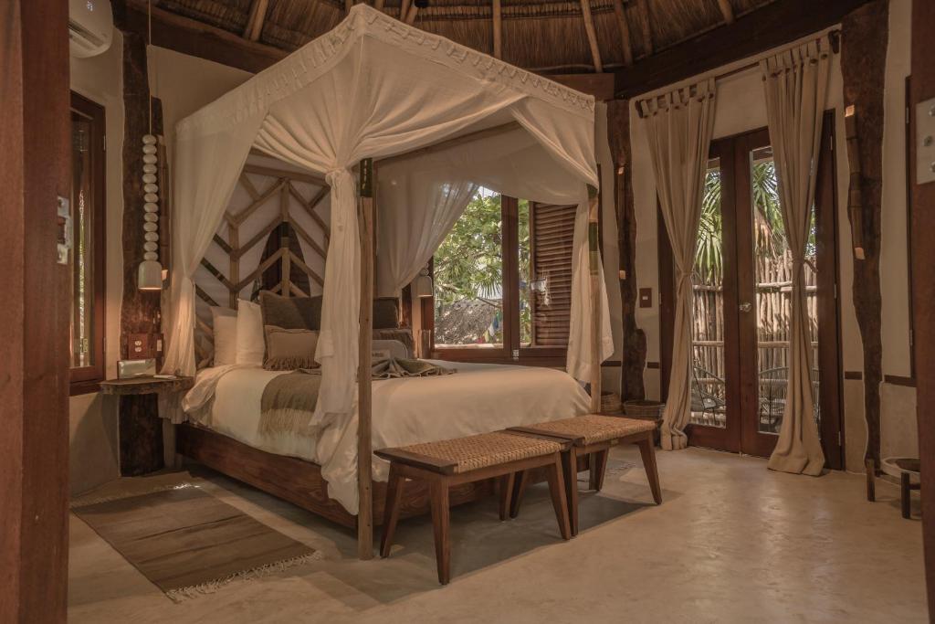 a bedroom with a canopy bed and a bench at Delek Tulum in Tulum