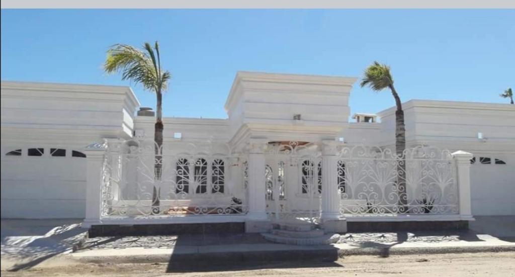 a white house with a gate and palm trees at Brenda alicia in Puerto Peñasco