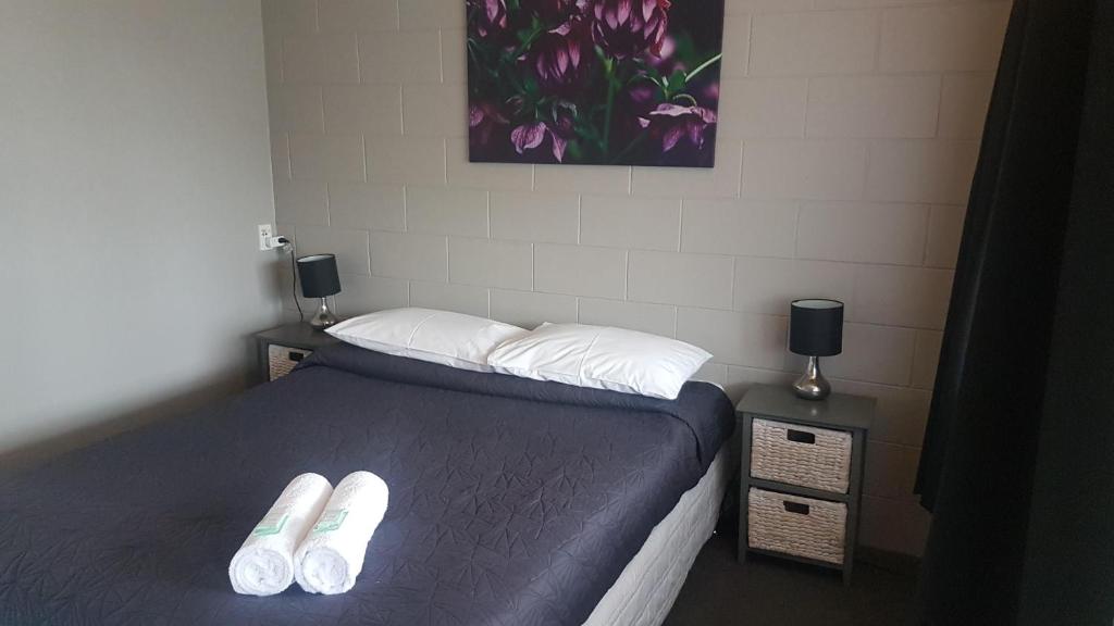a bedroom with a bed with two slippers on it at Railway Hotel/Motel Hokitika in Hokitika