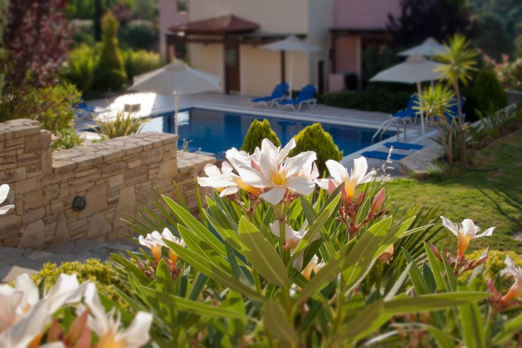 un jardín con flores blancas y una piscina en Eligia Villas, en Mixórrouma