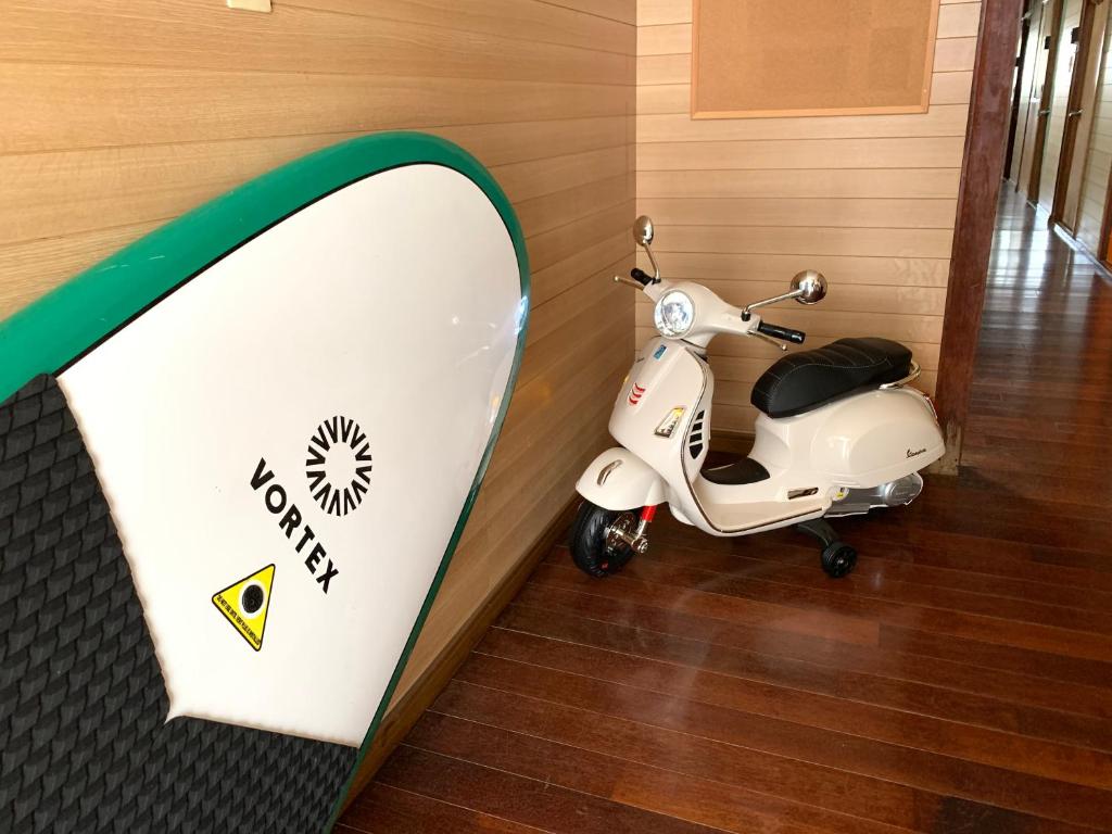 a scooter parked next to a wall with a sign at Ishigakijima Guesthouse Seacoro in Ishigaki Island