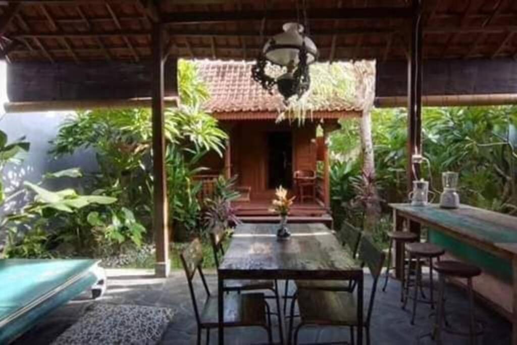 a patio with a table and chairs and a house at Klotok Surf Shack in Klungkung