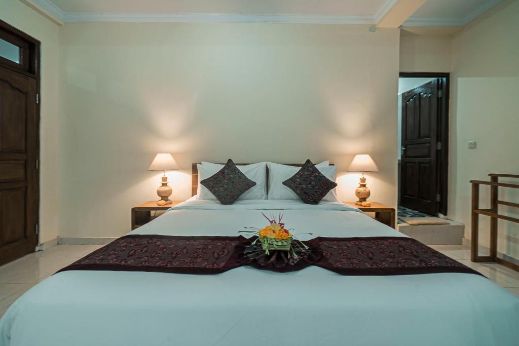 a bedroom with a large white bed with flowers on it at Vaneka Garden House in Ubud