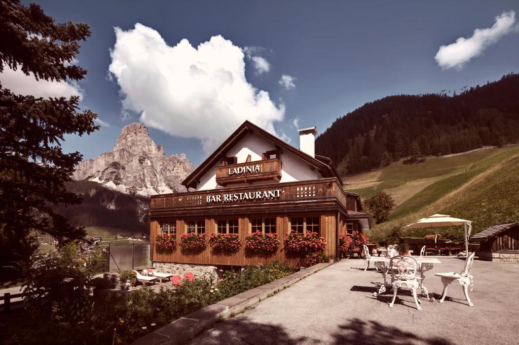 un edificio con mesas y sillas delante de él en Berghotel Ladinia, en Corvara in Badia