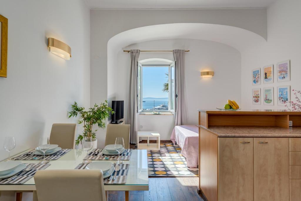 a living room with a dining table and a bedroom at Apartments Riva Lucija in Split