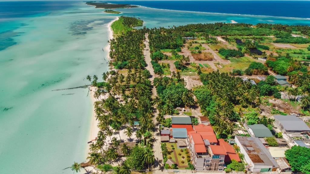 een luchtzicht op een strand met huizen en bomen bij Reveries Maldives in Gan