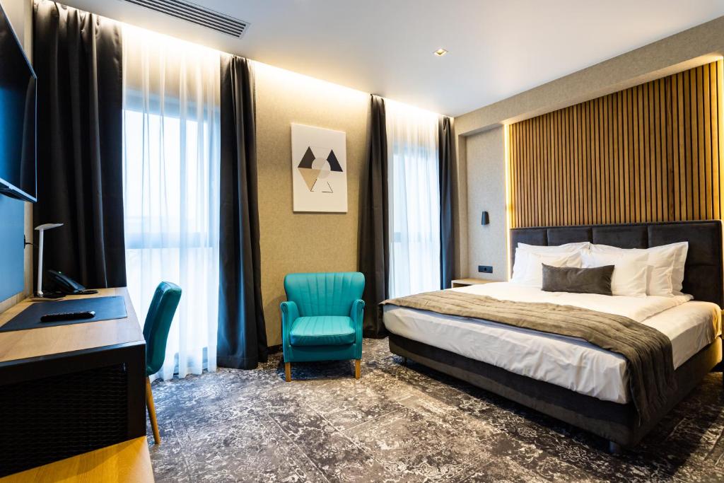 a bedroom with a bed and a desk and a chair at Hugo Hotel in Satu Mare