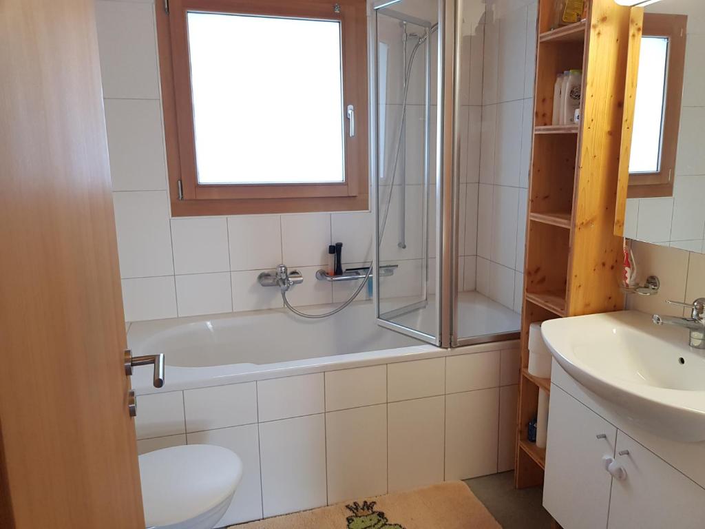 Un baño con bañera, inodoro y lavabo. en Neuwertige 3 ½ Zimmer-Wohnung in Zillis/Andeer, en Zillis