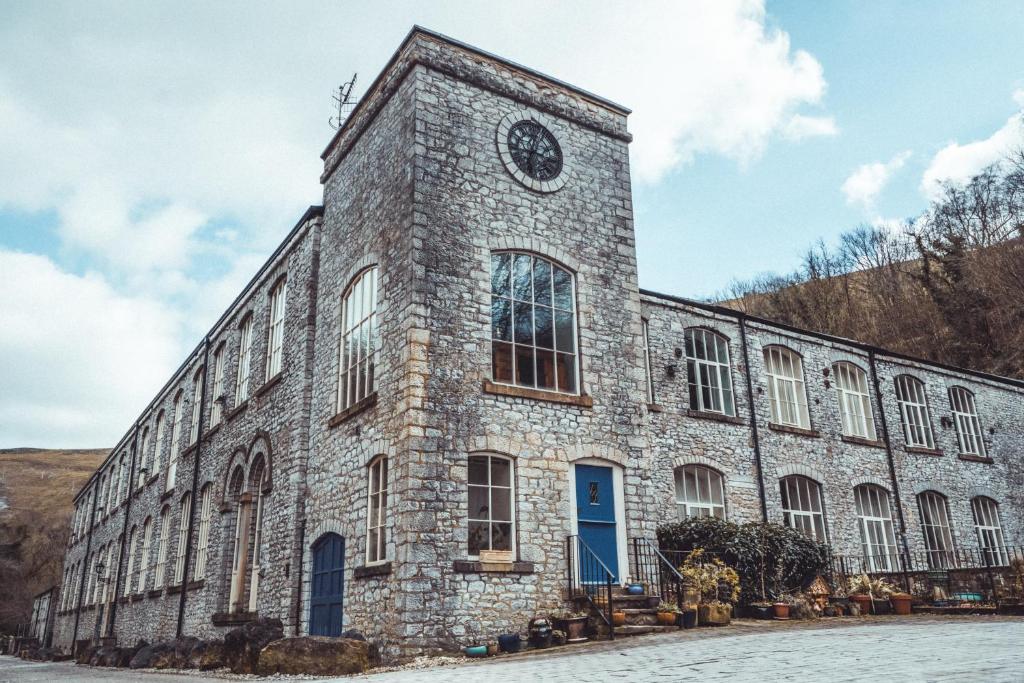 um grande edifício de pedra com um relógio em Litton Mill Retreat, Luxury Converted Mill em Cressbrook