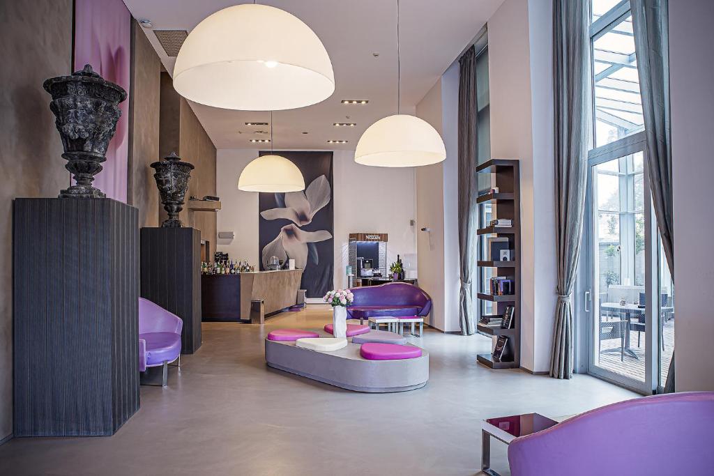 - un hall avec des chaises violettes et une table dans une pièce dans l'établissement Hotel For You, à Cernusco sul Naviglio