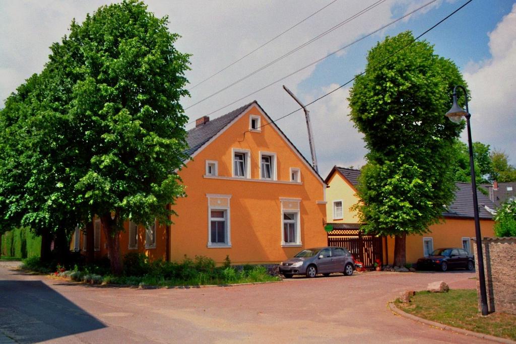 een oranje huis met een auto ervoor geparkeerd bij Alte Weberei in Straupitz