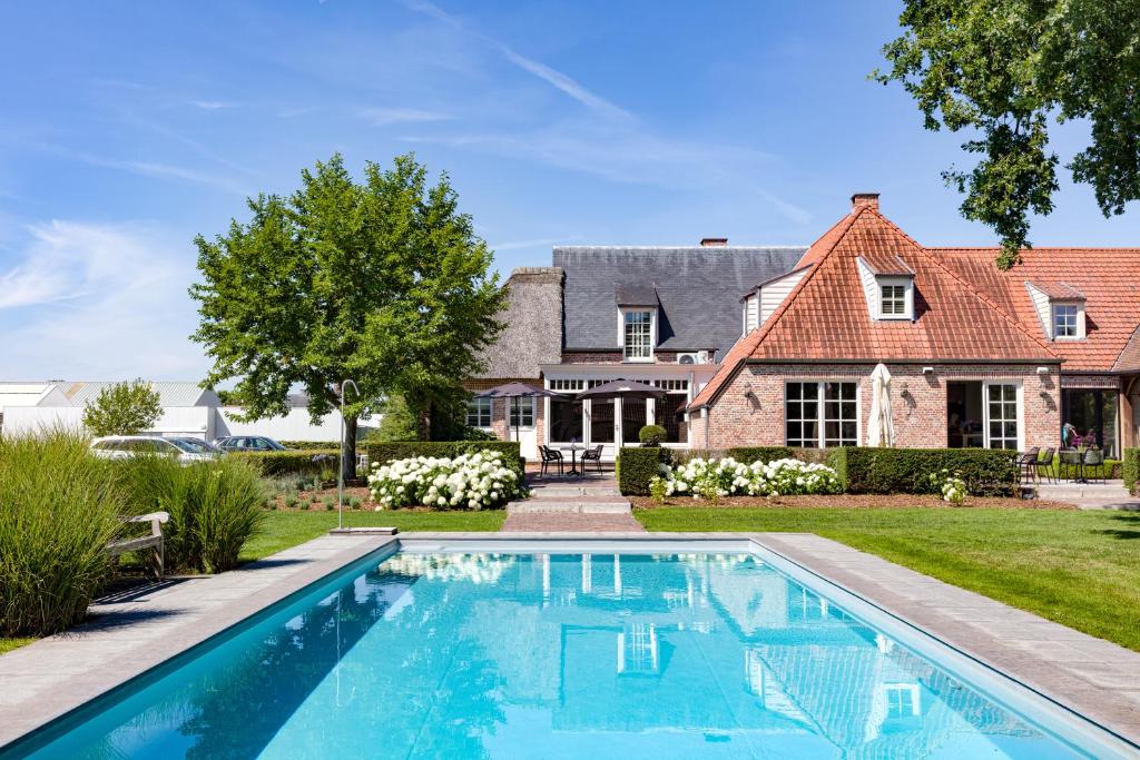 uma casa com piscina em frente a uma casa em B&B Rosselaer em Balen