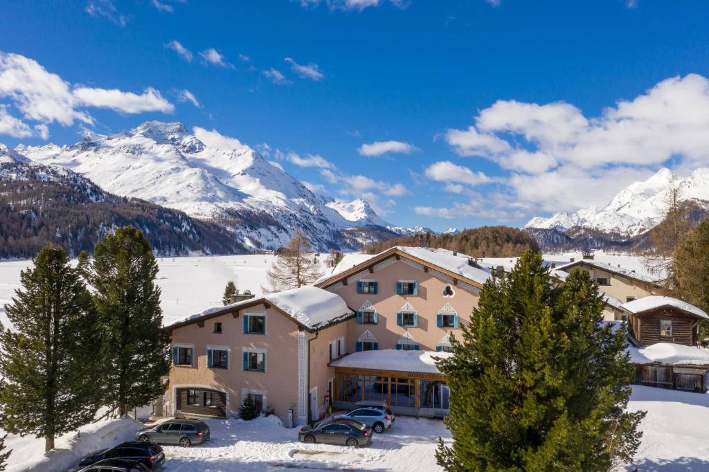 シルス・マリアにあるホテル チェサ ランドリーナの雪に覆われた山々を背景にしたリゾート