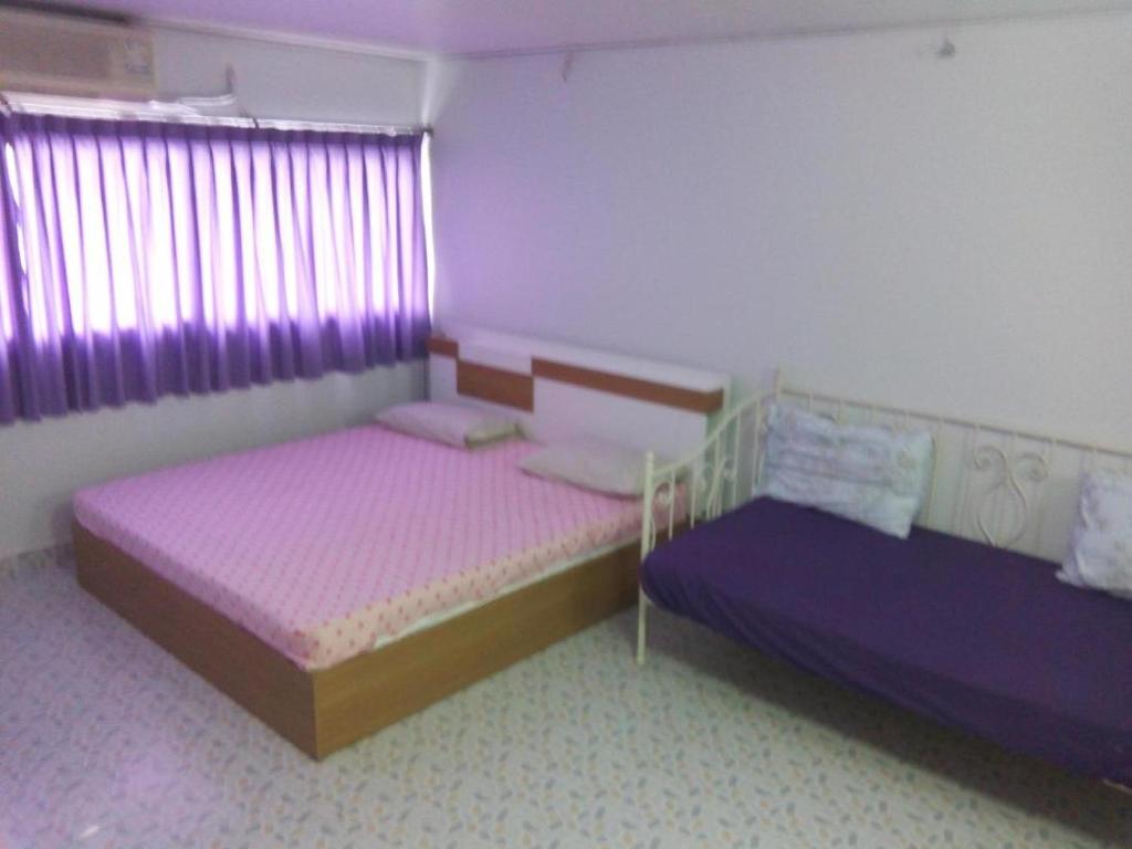 two beds in a room with purple curtains at Room in Guest room - Chan Kim Don Mueang Guest House, free parking space and free Wifi in Thung Si Kan