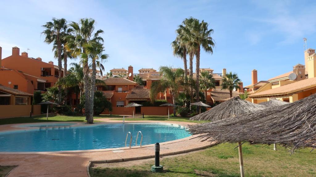 a large swimming pool with palm trees and buildings at Beach Huisje Mar Menor in Mar de Cristal