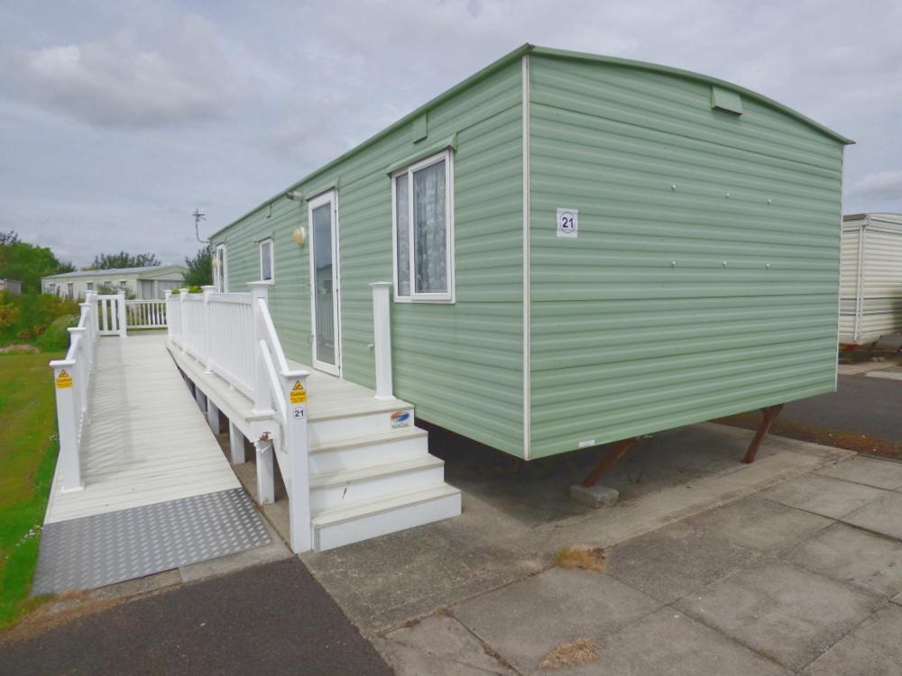 a green tiny house with a porch and stairs at DISABLED ACCESS Orchards 21 at Southview Leisure Park in Lincolnshire