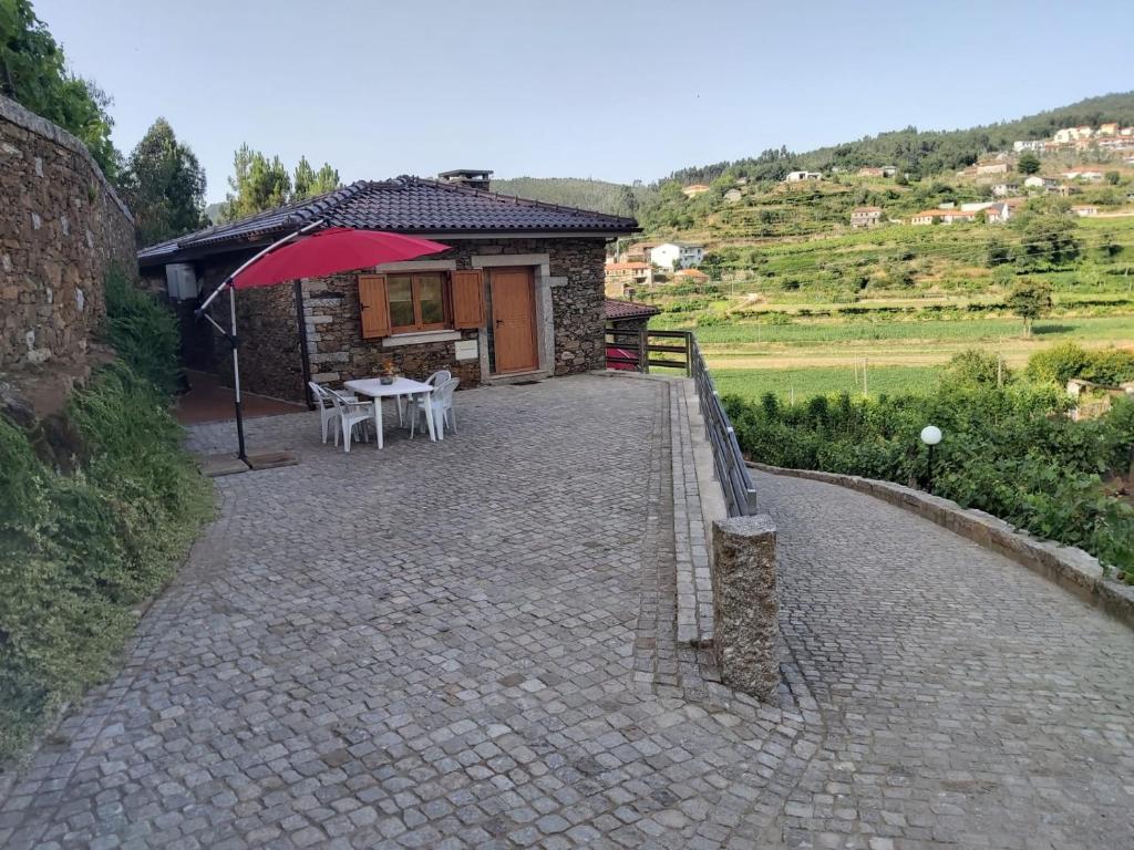 a patio with a table and an umbrella in front of a building at Casa do Tio Quim in Castelo de Paiva