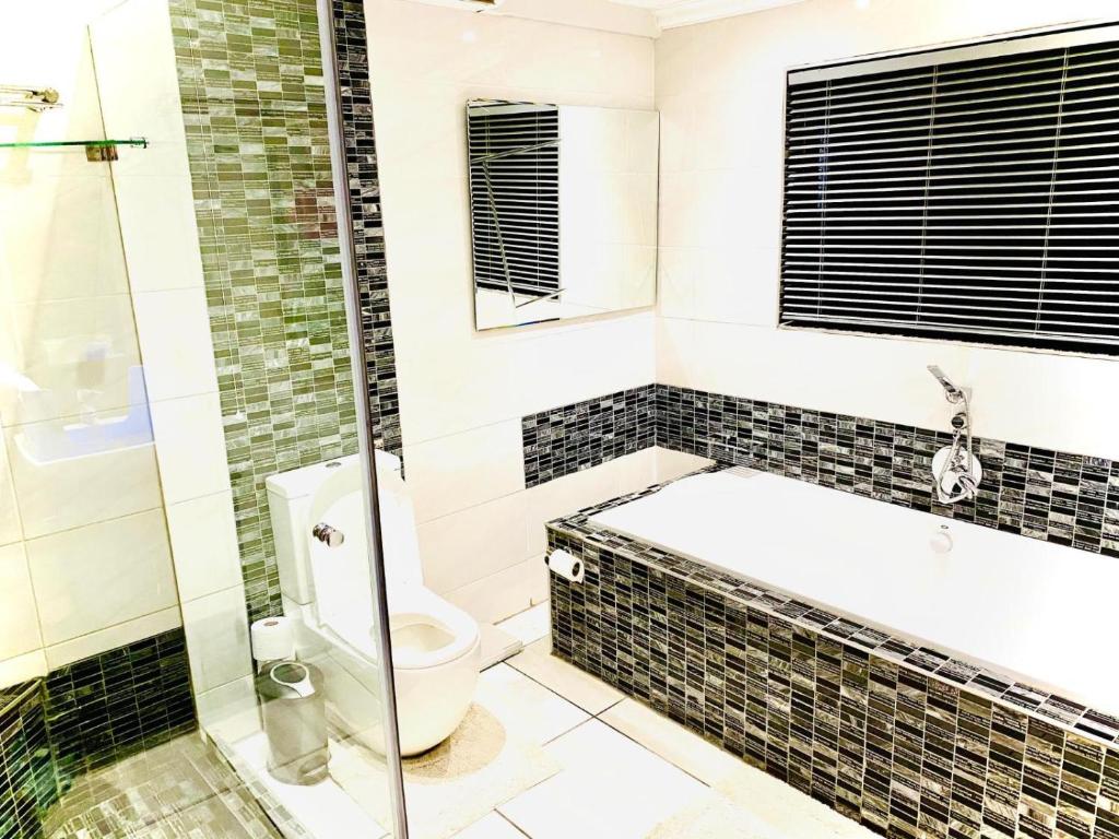 a bathroom with a toilet and a glass shower at C&C HOTEL VIBES Randpark Ridge JHB 14 Units Available in Boskruin