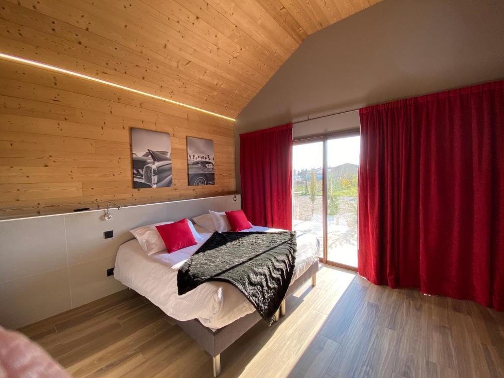 a bedroom with a bed with red curtains and a window at World Hotel in Saint-Vulbas