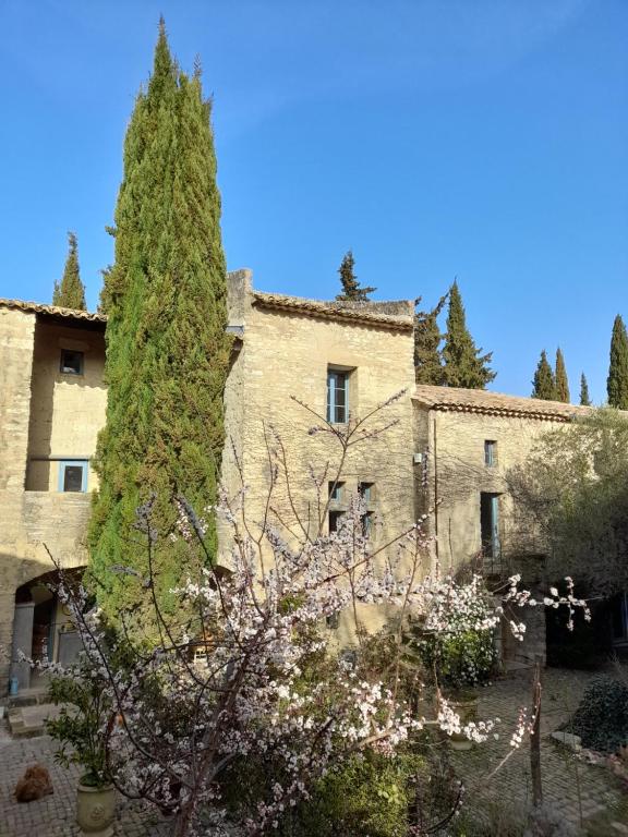 un vieux bâtiment en pierre avec un arbre en face de lui dans l'établissement Le Mas du Lac, à Uzès