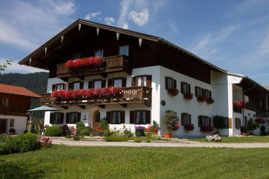 un grand bâtiment avec des boîtes de fleurs sur les balcons dans l'établissement Neuhaushof - Chiemgau Karte, à Inzell