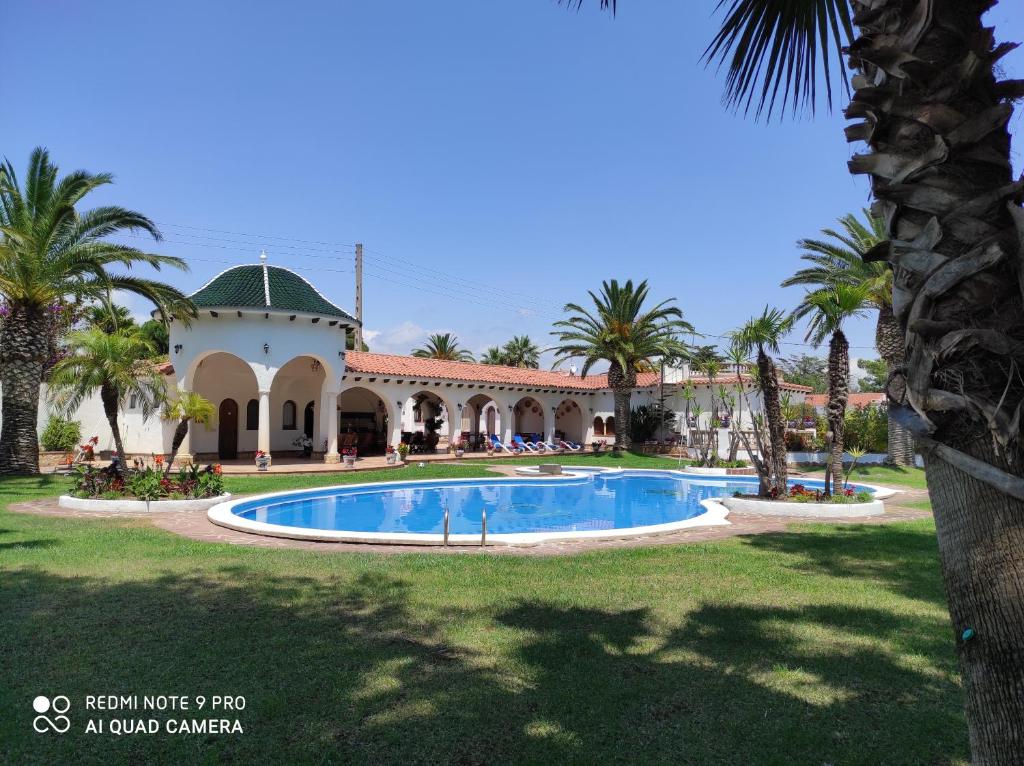 een villa met een zwembad en palmbomen bij Villa Balneari Resort Casa de vacances familiar in Montroig