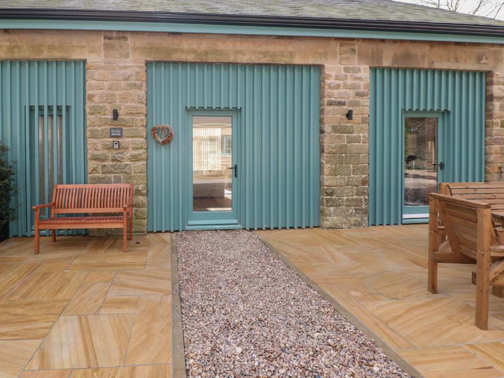 a building with green doors and a patio at Holly Cottage in Sheffield
