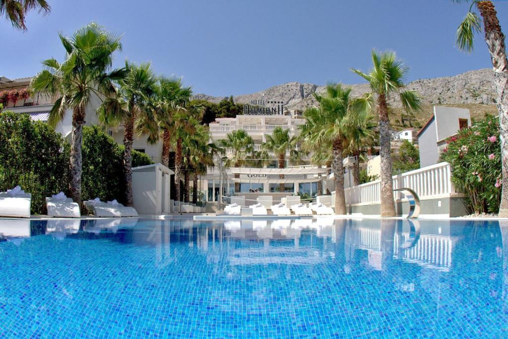 una gran piscina con palmeras y un edificio en Damianii Luxury Boutique Hotel & Spa, en Omiš