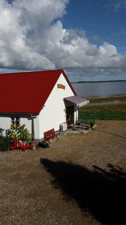 a white barn with a red roof next to the water at KristiansBorg in Nykøbing Mors
