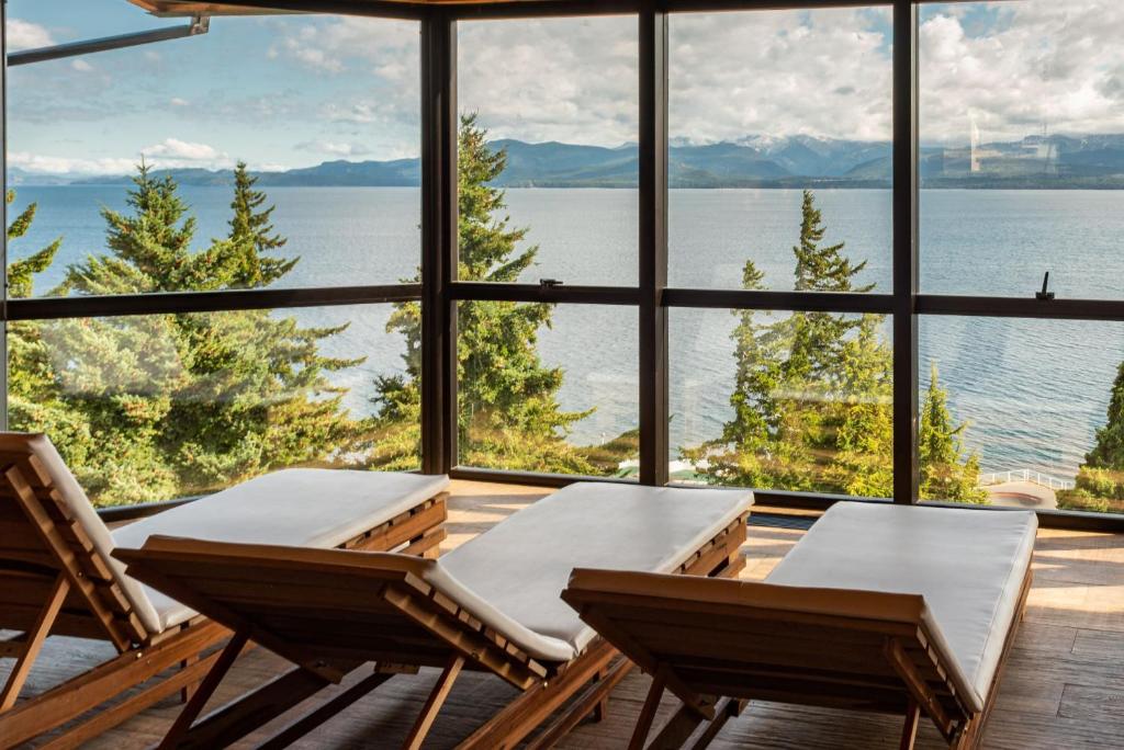 una camera con due sedie e vista sull'acqua di Hotel Alt Interlaken a San Carlos de Bariloche