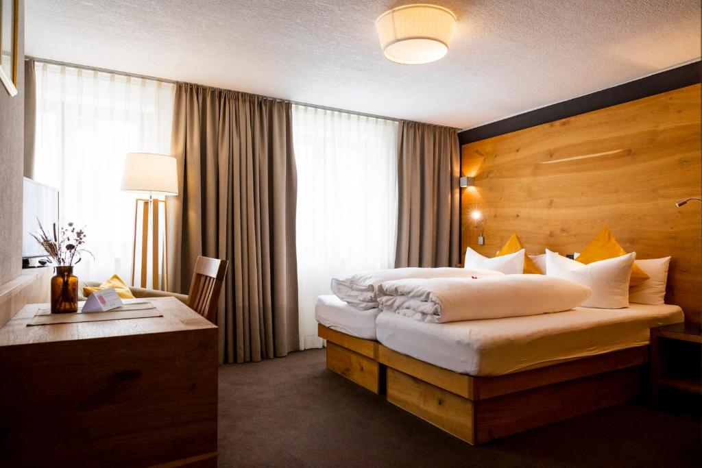 a hotel room with two beds and a desk at Hotel Montfort in Sankt Anton am Arlberg