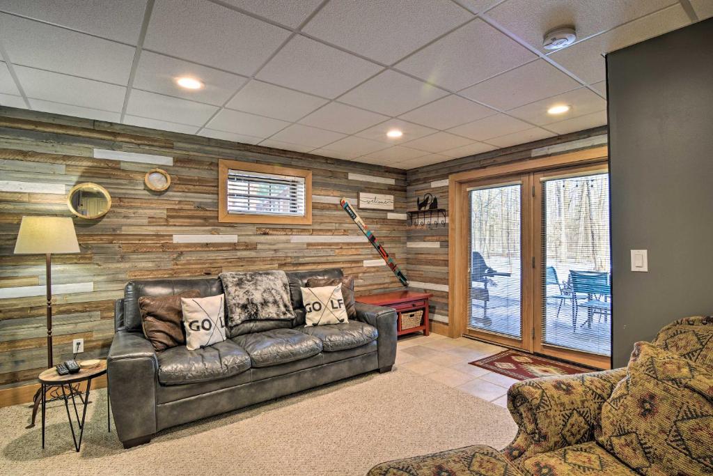 a living room with a leather couch and wooden walls at Boyne Falls Hideaway - Walk to Mountain Resort! in Boyne Falls