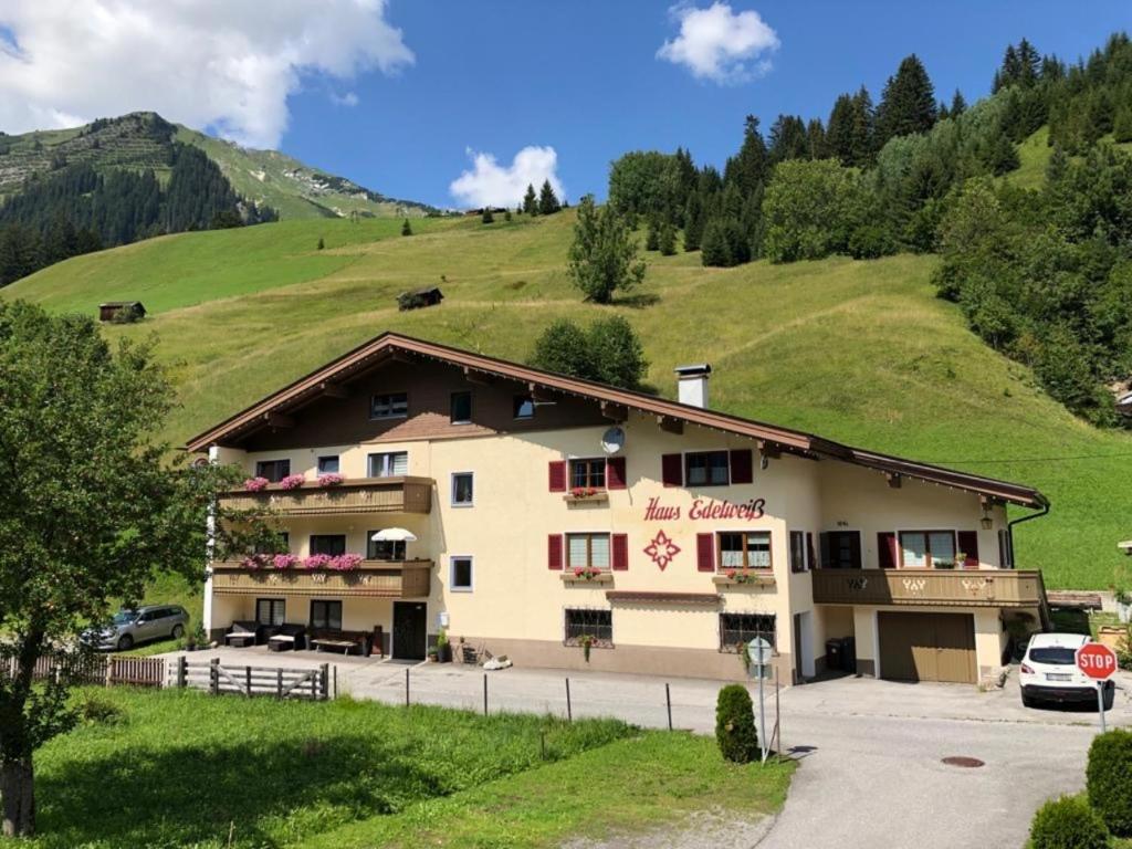 a building in the middle of a green hill at Pension & Ferienwohnungen Haus Edelweiß in Holzgau