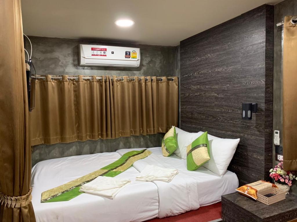 een slaapkamer met een bed met witte lakens en groene kussens bij Amazon Resort in Suratthani