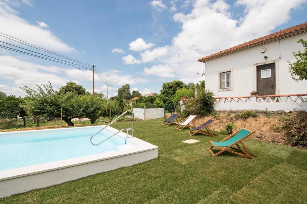 a backyard with a swimming pool and chairs and a house at Avó Rosa Guesthouse in São João da Ribeira
