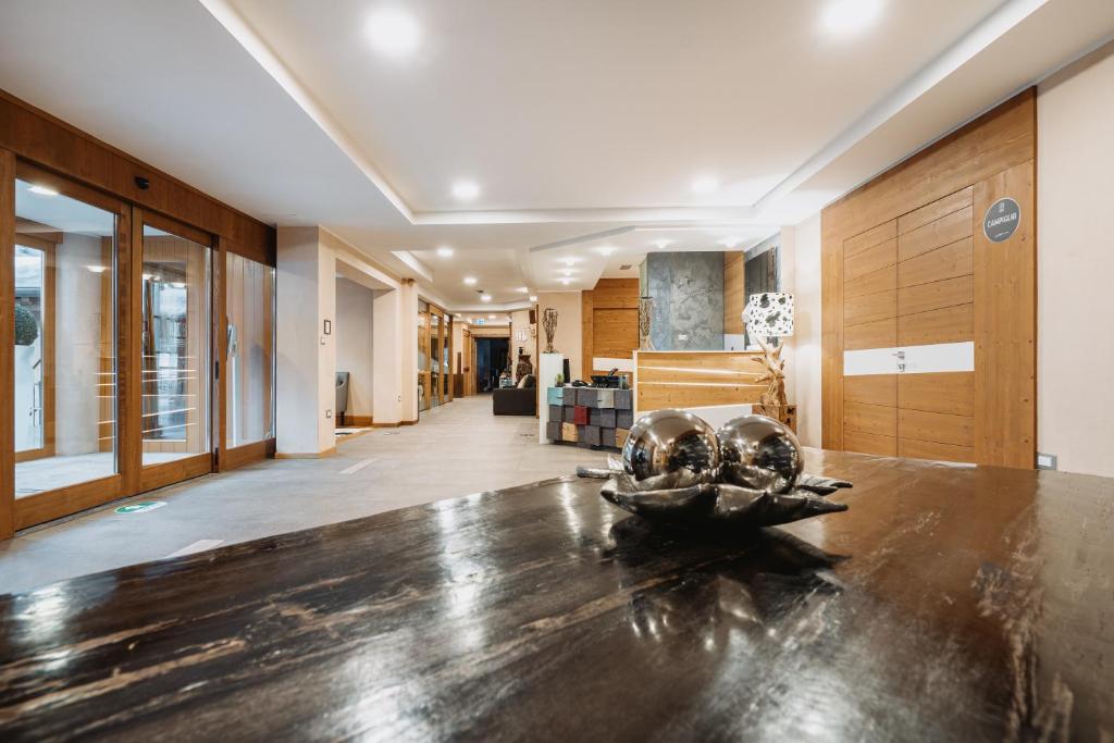 salon z drewnianym stołem i korytarzem w obiekcie Hotel Chalet Del Brenta w Madonna di Campiglio