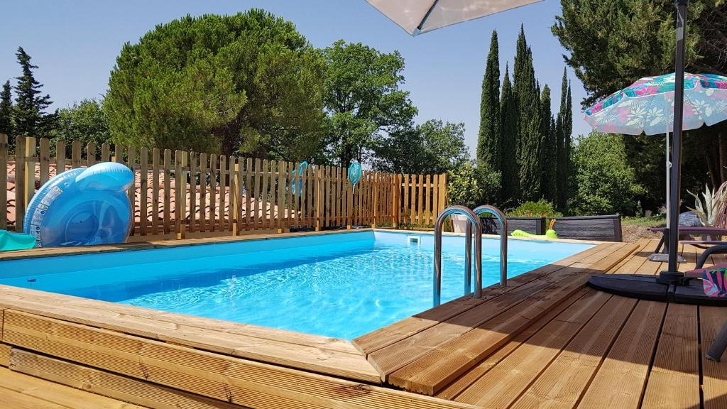 una pequeña piscina con terraza de madera y sombrilla en Mas Orféo, en Montauroux