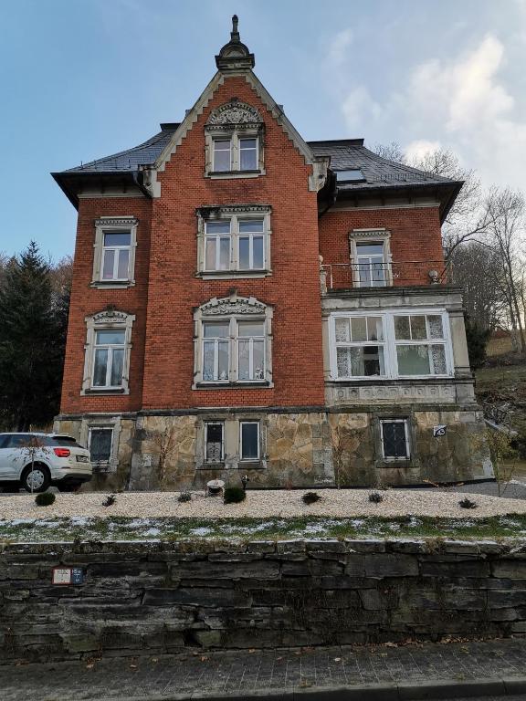 a large brick house with a car parked in front of it at Ferienwohnung Rote-Villa in Pobershau